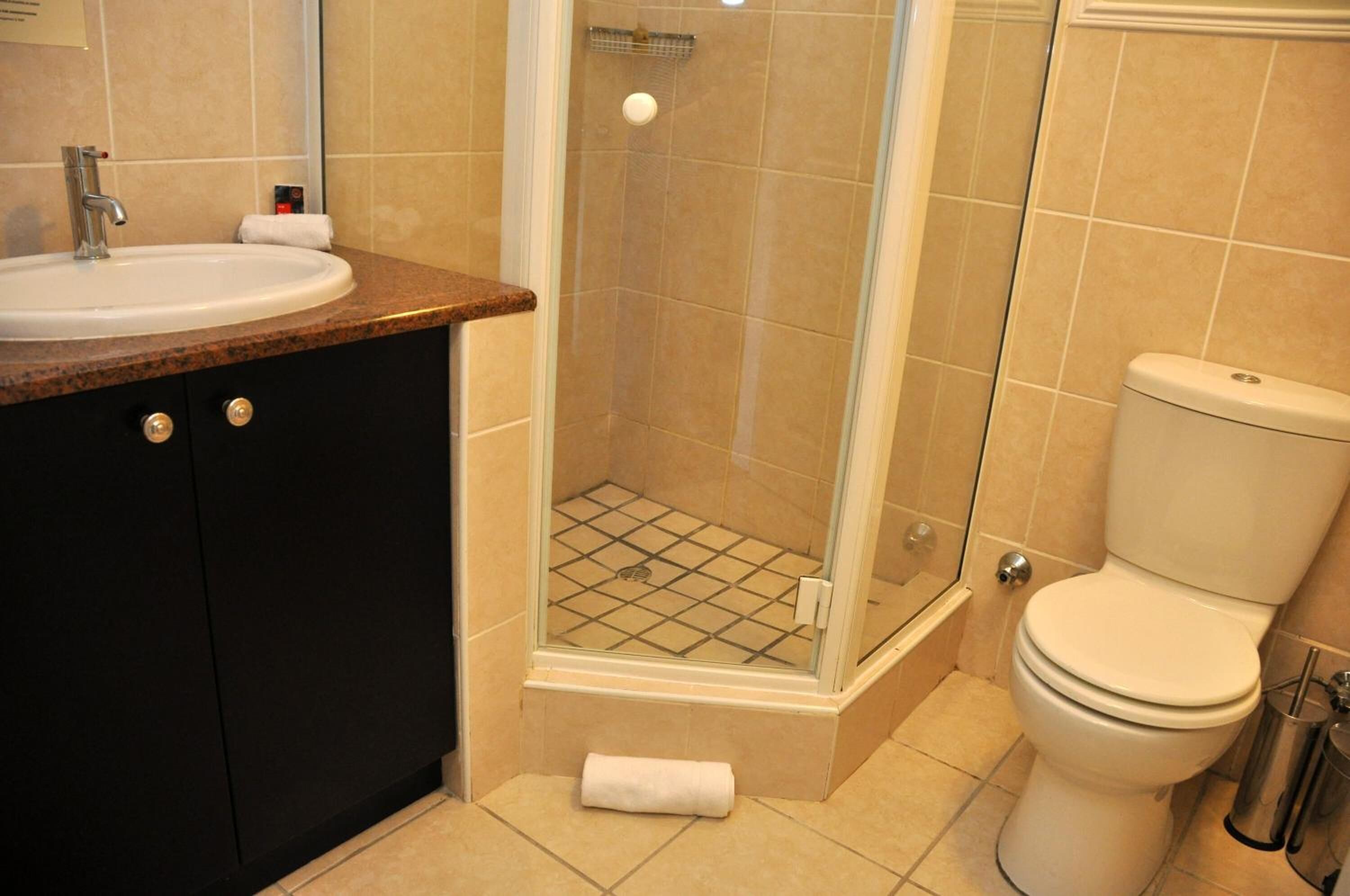 Une salle de bain équipée d’un lavabo, de toilettes et d’une douche à parois de verre.
