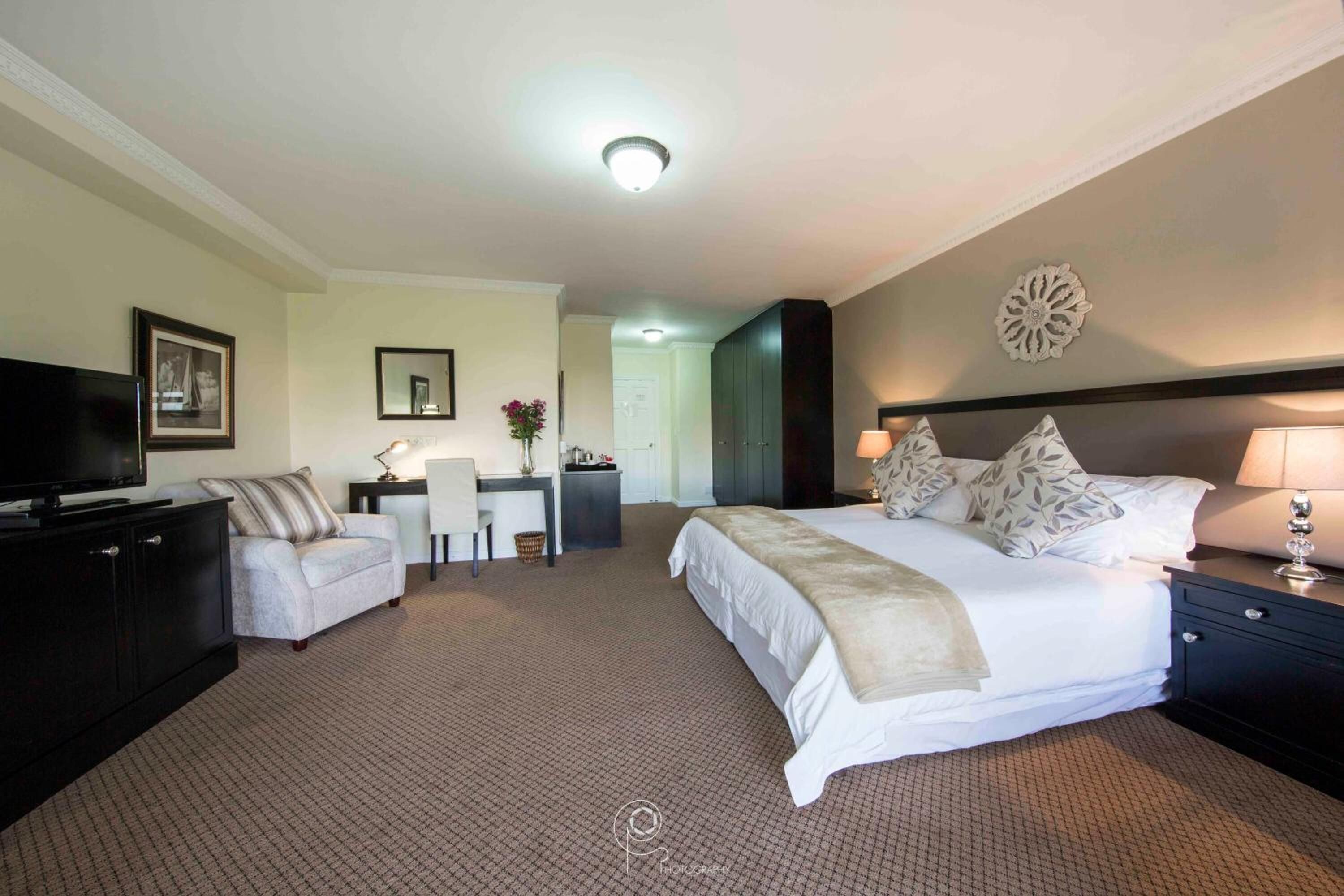 Une chambre d’hôtel avec un grand lit, un bureau, une télévision et une chaise.