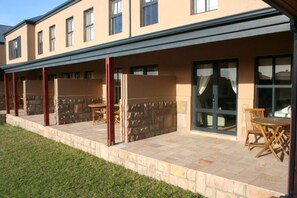 A building with a covered patio area, stone walls, and large windows.