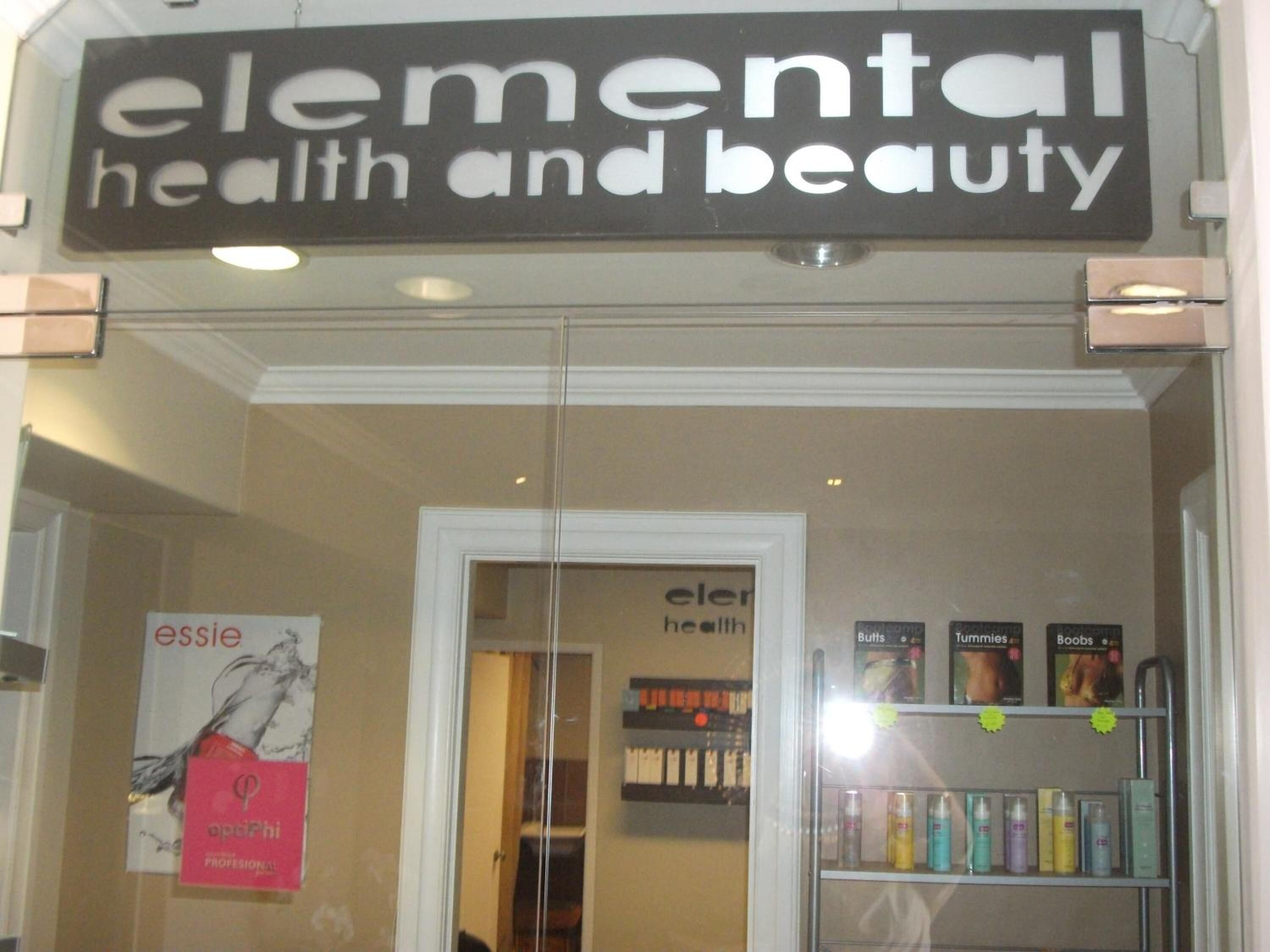 La entrada de una tienda llamada 'elemental health and beauty', con una puerta de vidrio y un letrero encima.