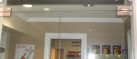 The entrance of a store named 'elemental health and beauty' with a glass door and a sign above it.