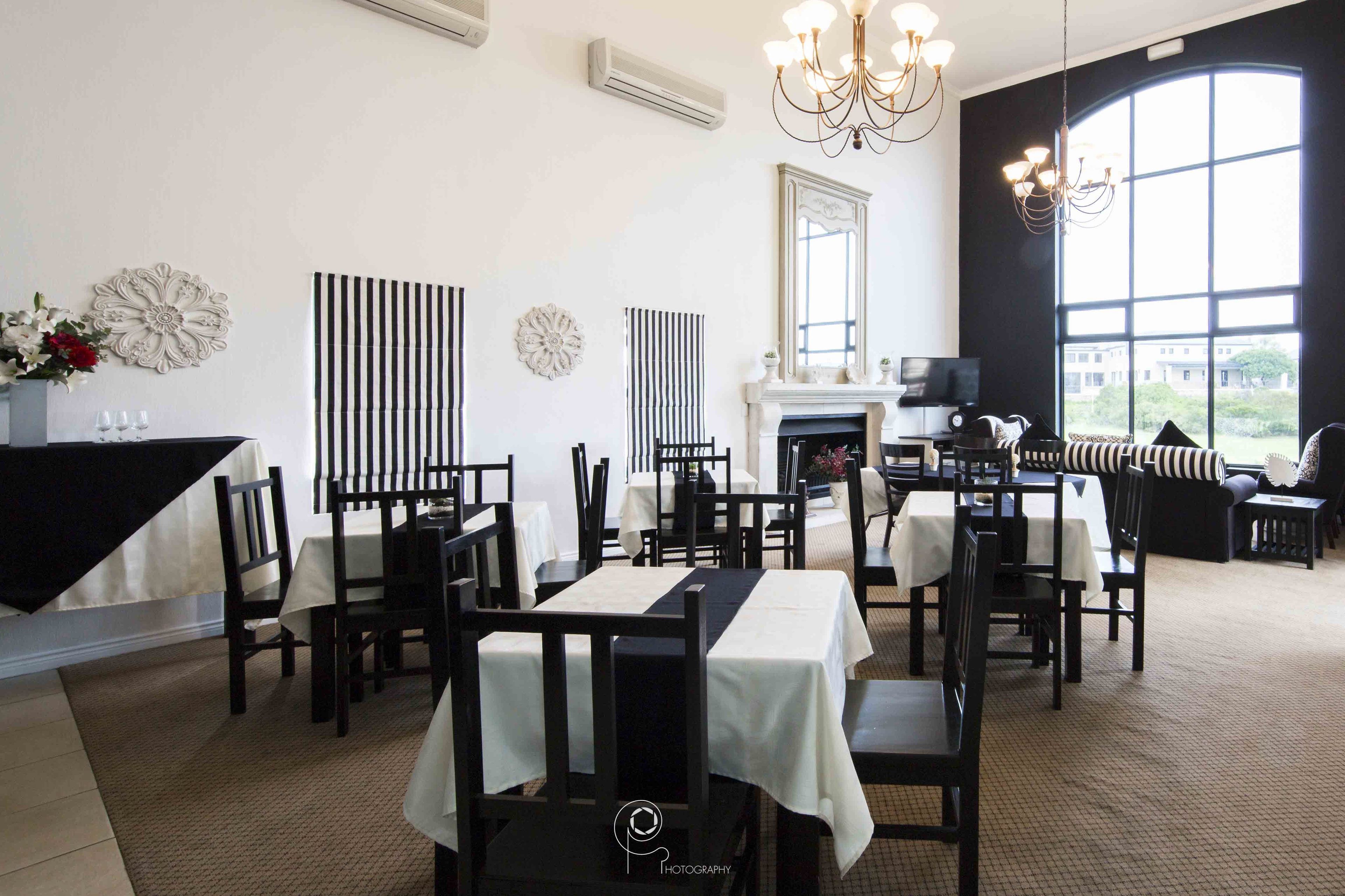 A dining area with tables and chairs, a fireplace, and decorative wall art.