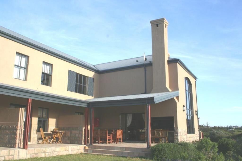 Une maison à deux étages dotée d’un patio couvert, de grandes fenêtres et d’une cheminée.