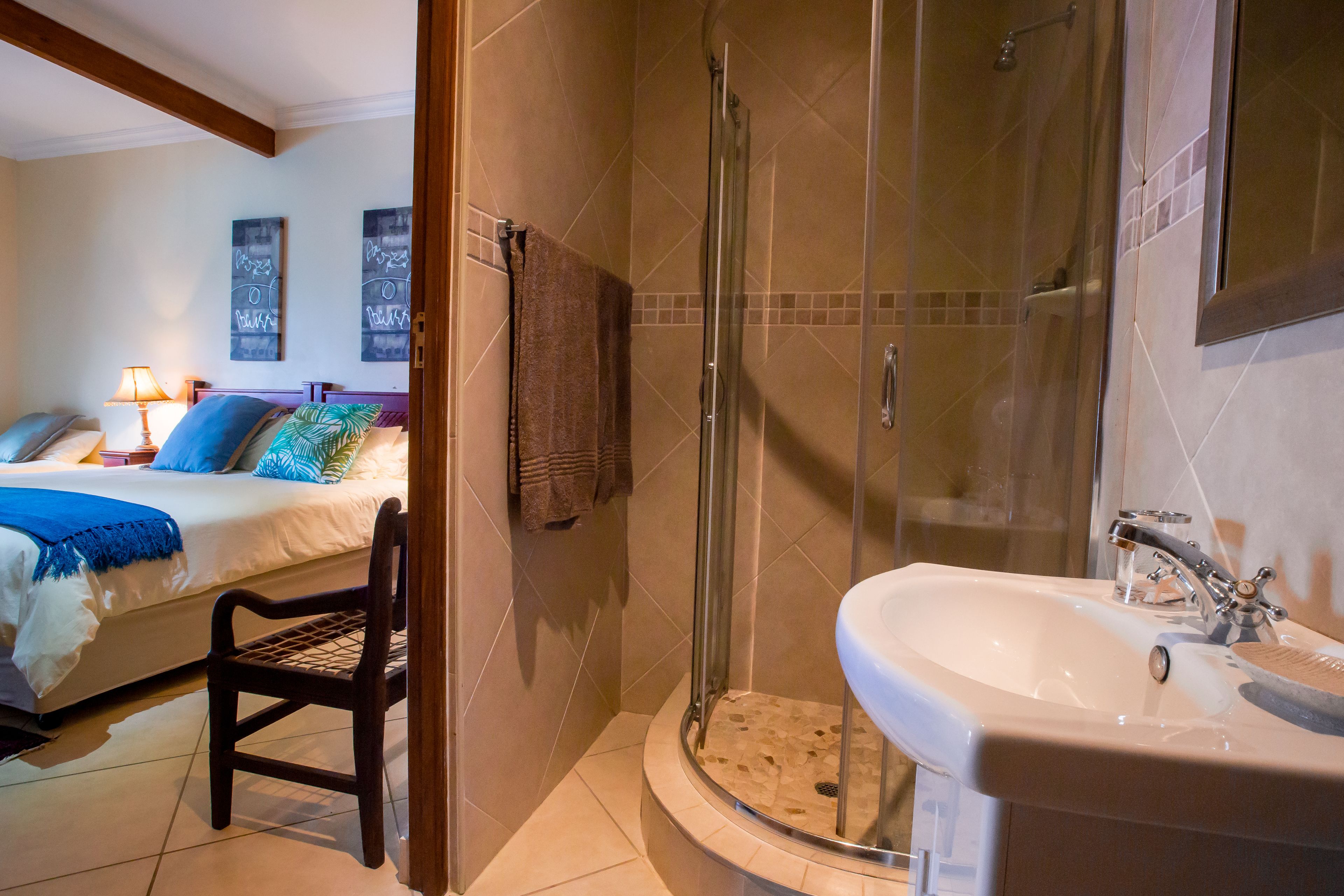 Una habitación de hotel con cama, una silla, ducha y lavamanos.