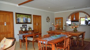 A dining area with wooden tables and chairs, a kitchen in the background, and a large framed family photo on the wall. - Turtle Bay Lodge (St. Lucia)