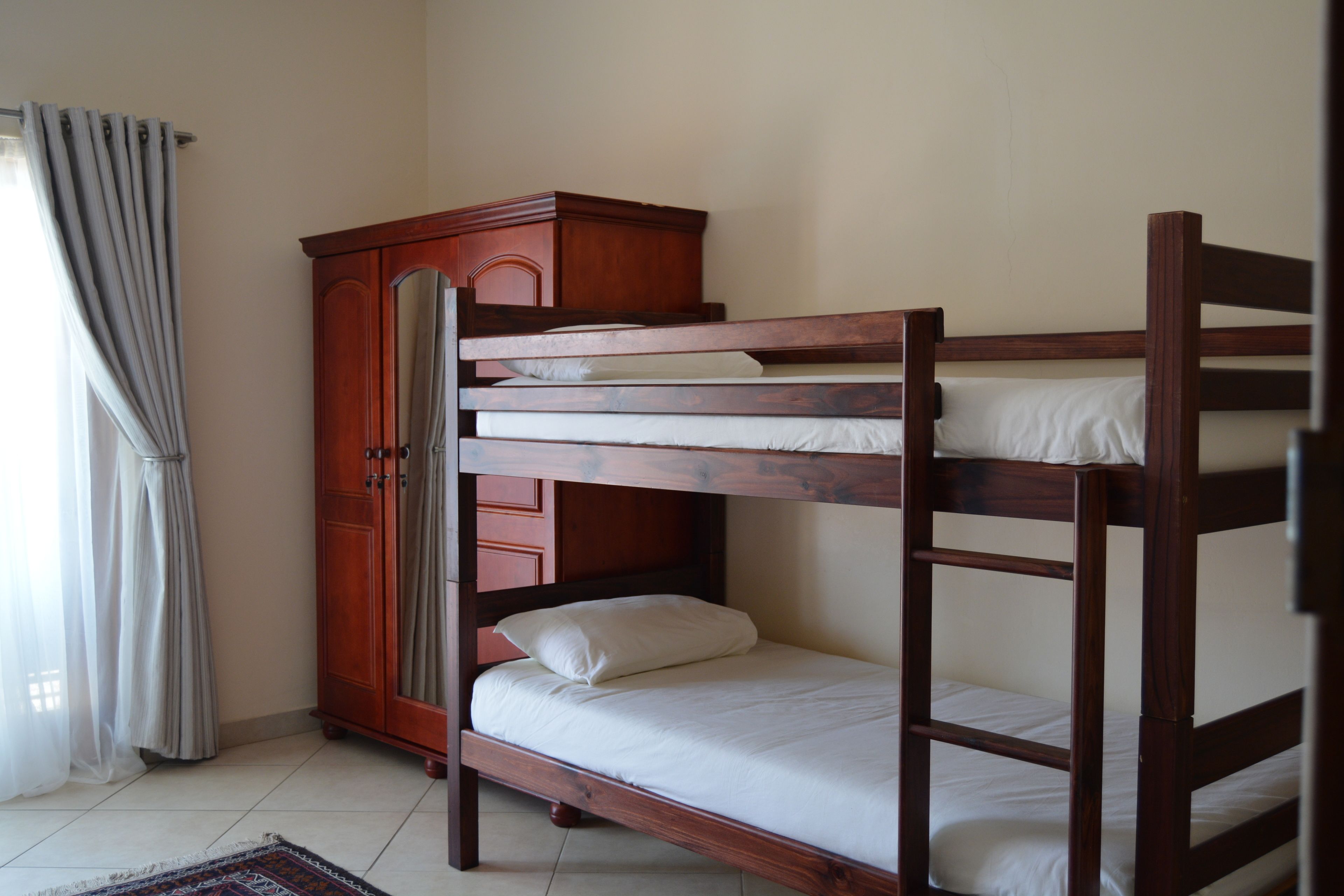 A bunk bed with a wooden wardrobe beside it.