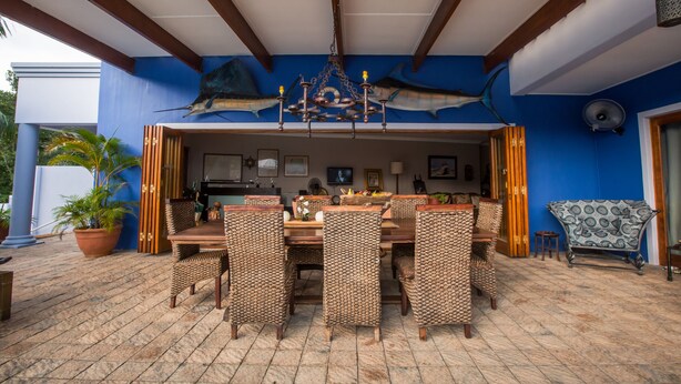 An outdoor dining area with wicker furniture, a wooden table, and a ceiling fan. - Turtle Bay Lodge (St. Lucia)