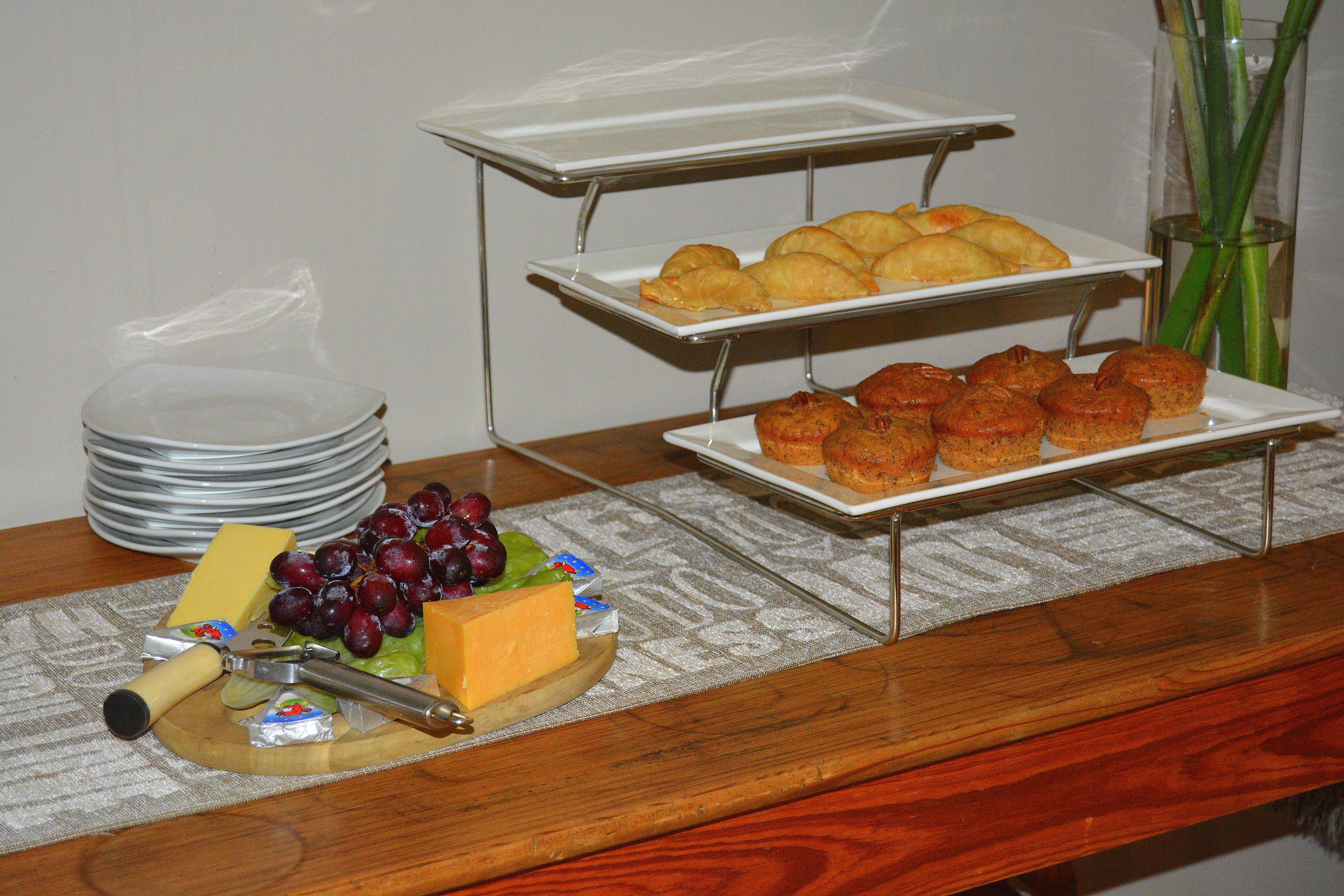 A buffet table with cheese, grapes, and various pastries.