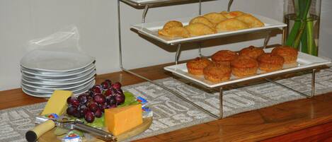 A buffet table with cheese, grapes, and various pastries.