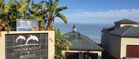 A sign for 'On the Rocks' accommodation with a view of the ocean.