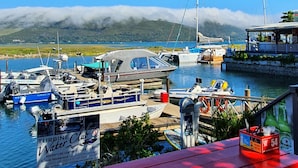 Un port de plaisance avec des bateaux amarrés, une terrasse en bois et un panneau indiquant un club nautique.