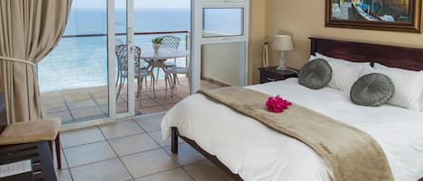Une chambre d’hôtel avec un lit, une chaise, une table et une vue sur l’océan.