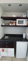 Uma cozinha compacta equipada com micro-ondas, pia e armários.
