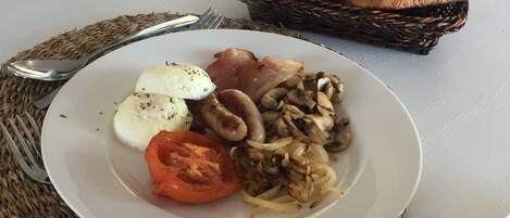 Un plato con mozzarella, tocino, champiñones y tomate sobre un plato blanco.