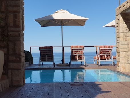Una piscina al aire libre, sillones reclinables de piscina