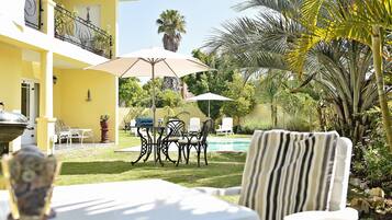 A yellow building with outdoor seating, a pool, and palm trees.