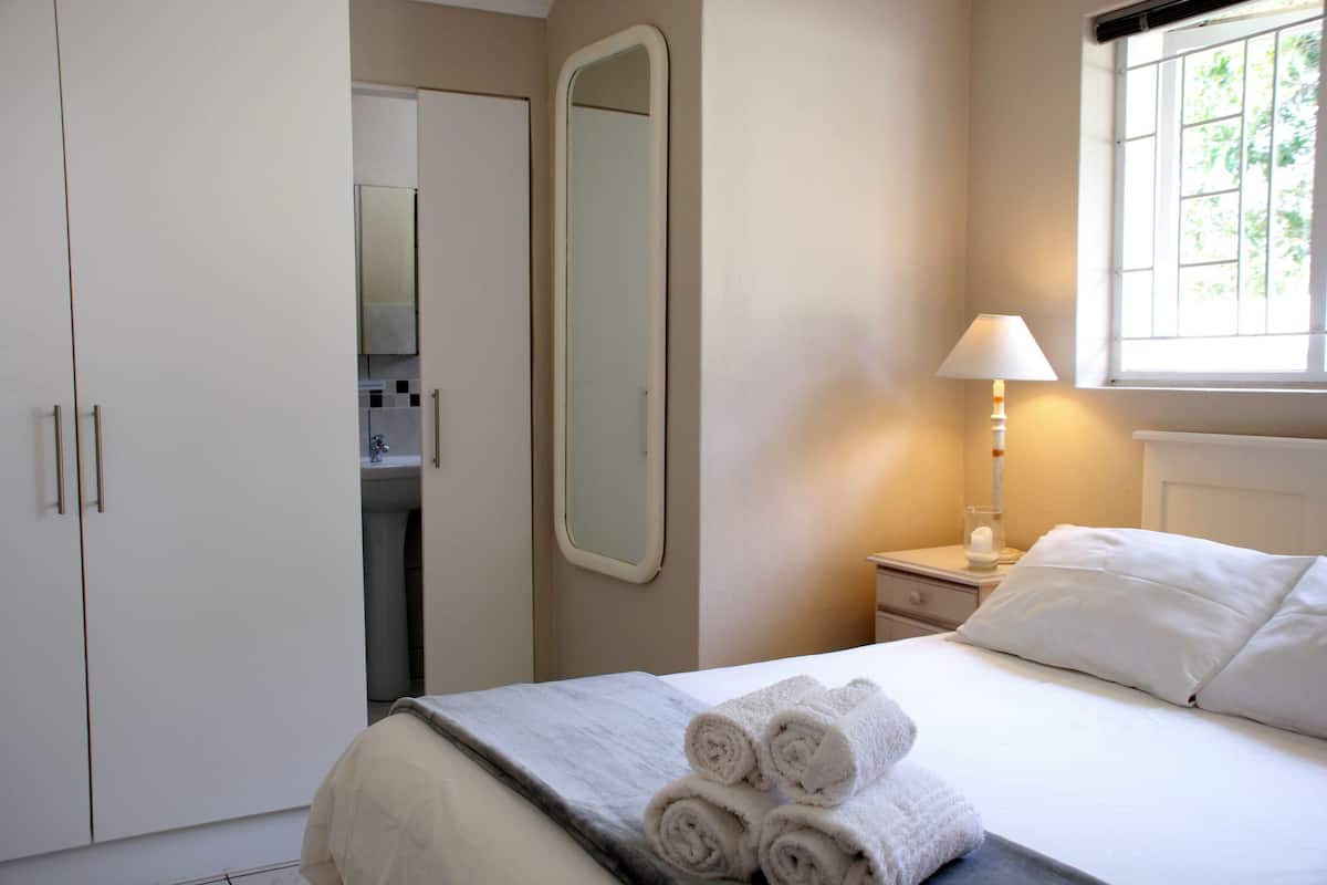 Ein Hotelzimmer mit einem Bett, einem Nachttisch, einer Lampe, einem Fenster und einem Kleiderschrank.