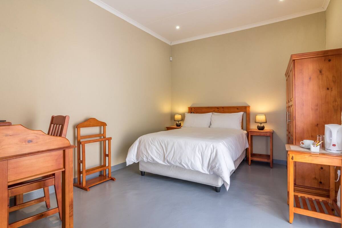 A bedroom with a bed, bedside tables, a wooden desk, and a cabinet.