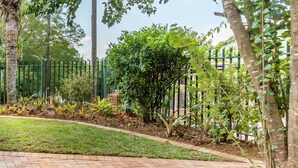 A paved pathway leading to a green area with a fence and trees. - Sabie Retreats Guest House (Sabie)