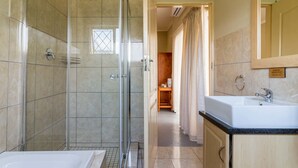 A modern bathroom with a glass-enclosed shower, a bathtub, a sink, and a vanity. - Sabie Retreats Guest House (Sabie)