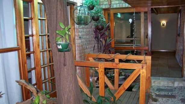 Una puerta de madera que da a un sendero de piedra, rodeada de macetas con plantas y una estructura de madera rústica.