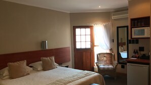 Una habitación de hotel con una cama, un escritorio, una silla, un microondas y un refrigerador.