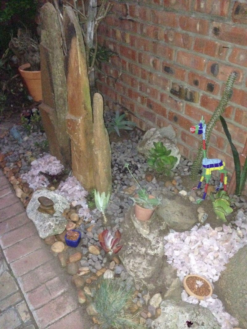 A garden with various plants, rocks, and a brick wall.