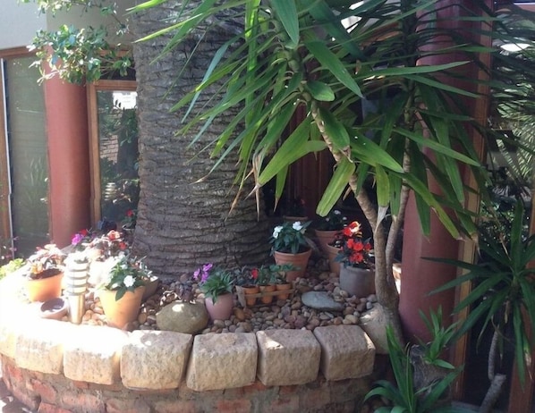 Un jardín con diversos maceteros y un muro de piedra.