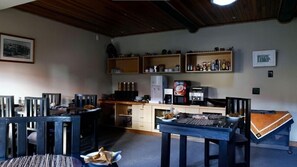 Una cocina acogedora con armarios de madera, una cafetera y un comedor con sillas y una mesa.