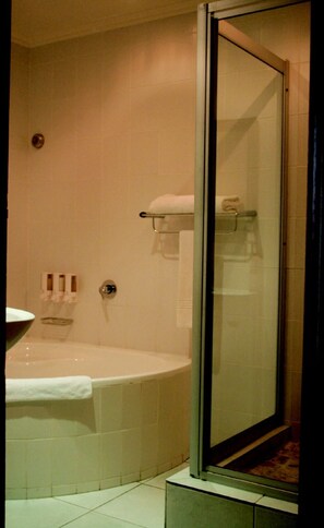 Een badkamer met een bad, een douchecabine van glas en een toilet.