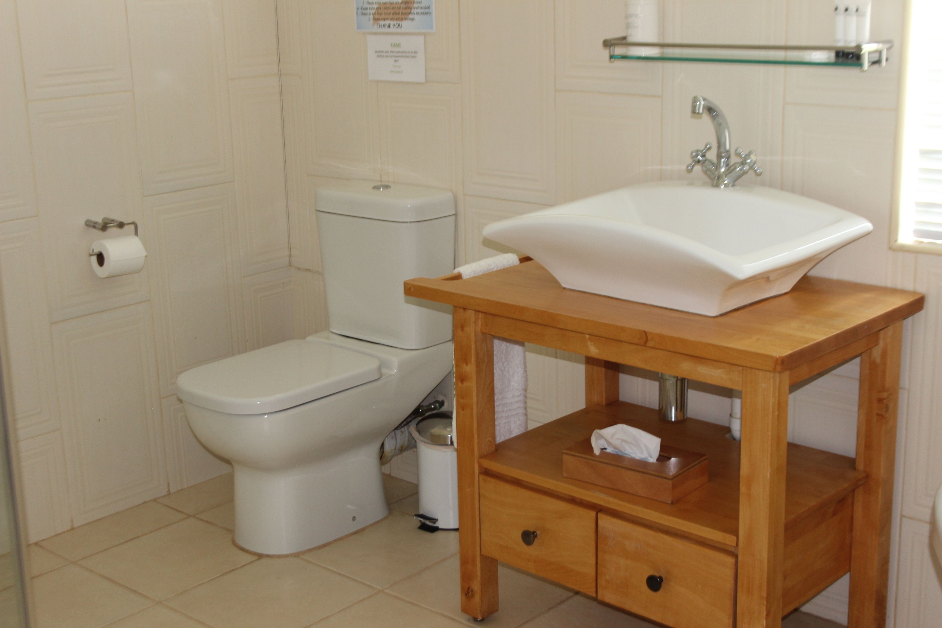 Et badeværelse med toilet, vask og et træskab.