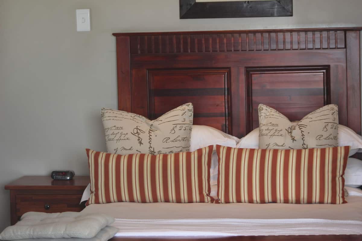 A neatly made bed with striped pillows and a wooden headboard.