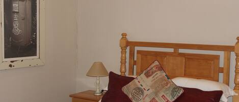 A bed with a wooden headboard, a nightstand with a lamp, and a wall-mounted mailbox.