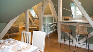 Un cuarto ático acogedor con comedor, cocina y zona de dormir entrepiso.