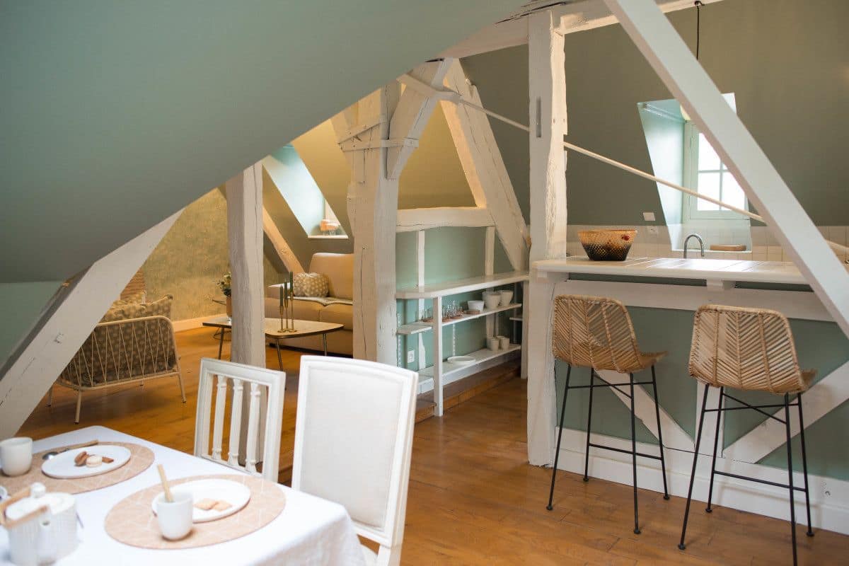 A cozy attic room with a dining area, a kitchen, and a lofted sleeping area.