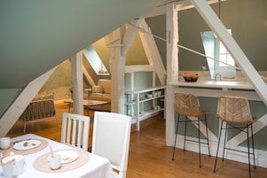 Un cuarto ático acogedor con comedor, cocina y zona de dormir entrepiso.