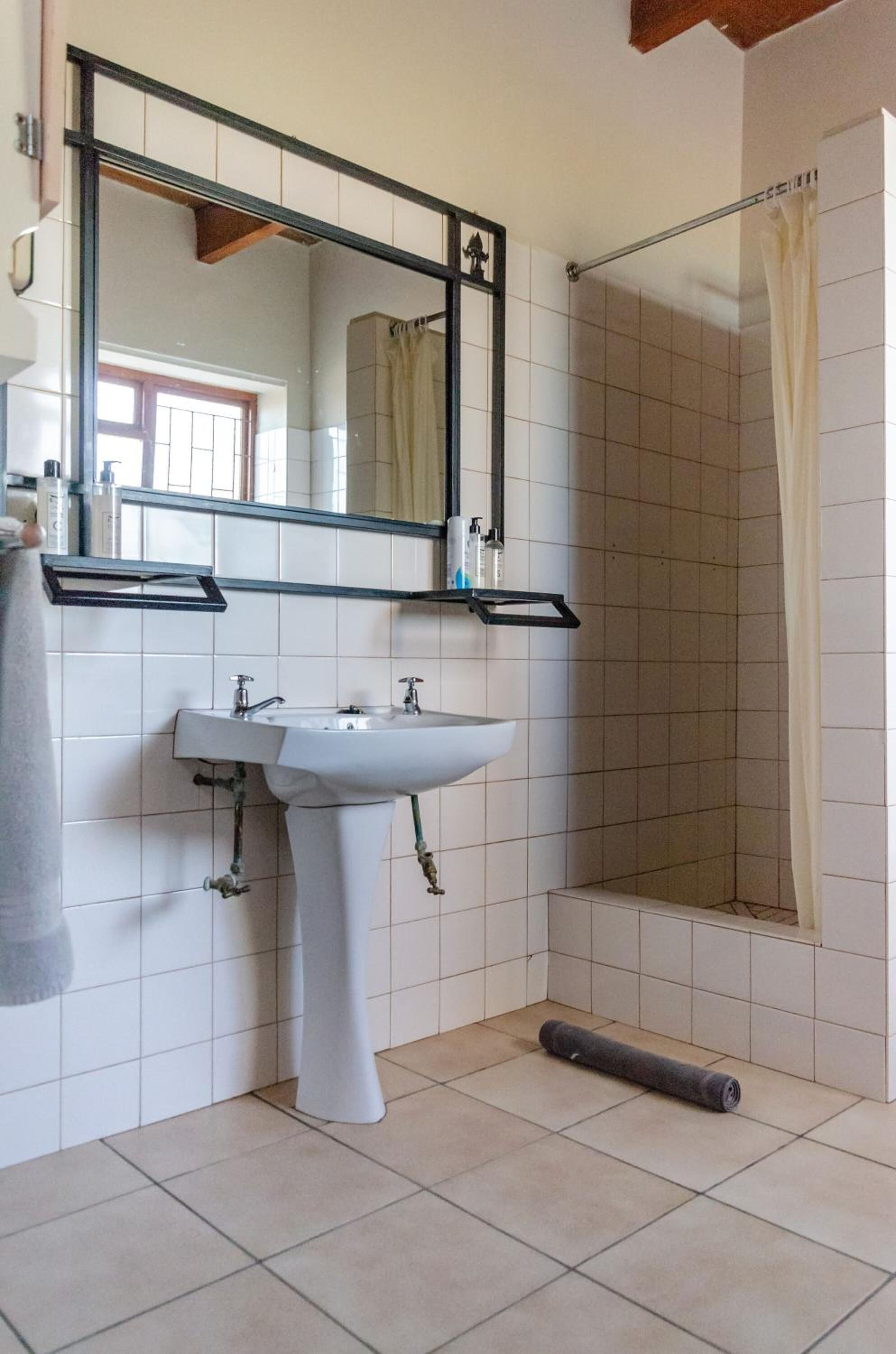 A bathroom with a white sink, a mirror, and a shower with a curtain.