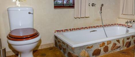 A bathroom with a toilet, a bathtub, and a window with curtains.