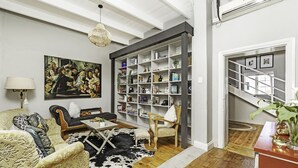 A living room with a sofa, armchair, coffee table, and a bookshelf filled with books and decorative items.