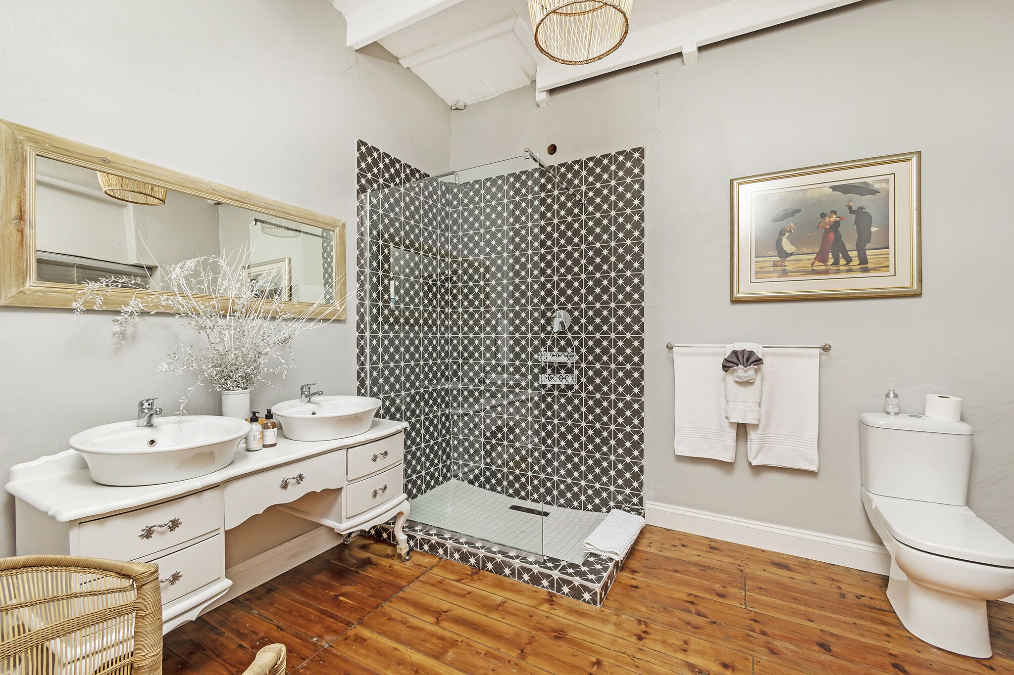 A bathroom with two sinks, a mirror, a shower, and a toilet.