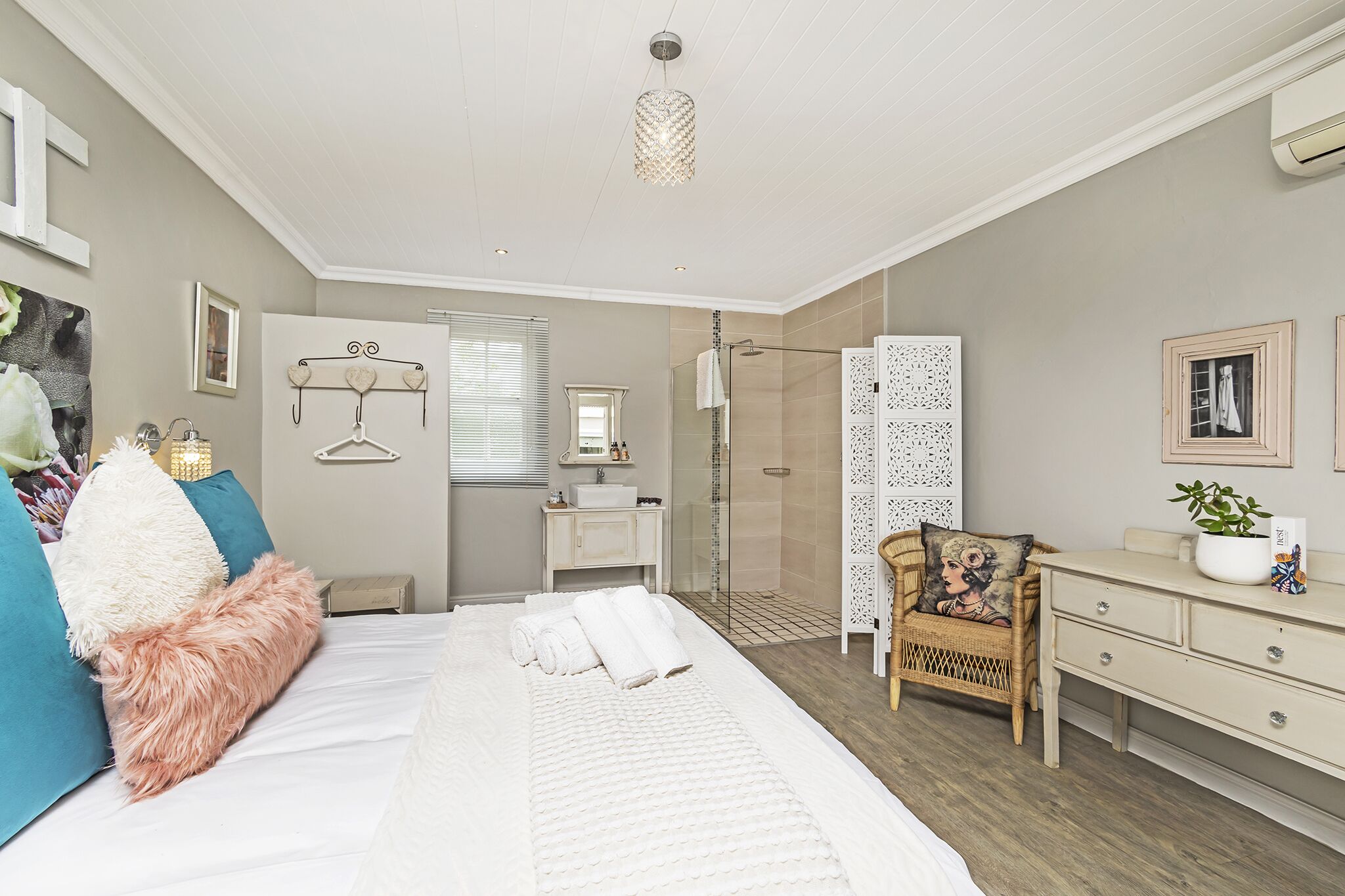 Un dormitorio moderno con una cama grande, una mesita de noche, una silla, un aparador y una zona de ducha.