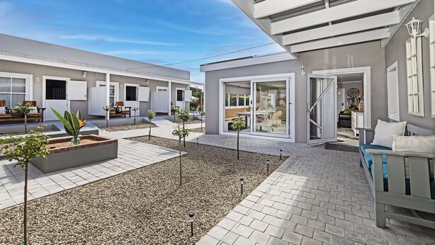A modern outdoor area with a patio, seating, and a small garden.