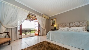 Un dormitorio con una cama, una silla, un tapete y vistas a través de una puerta abierta.