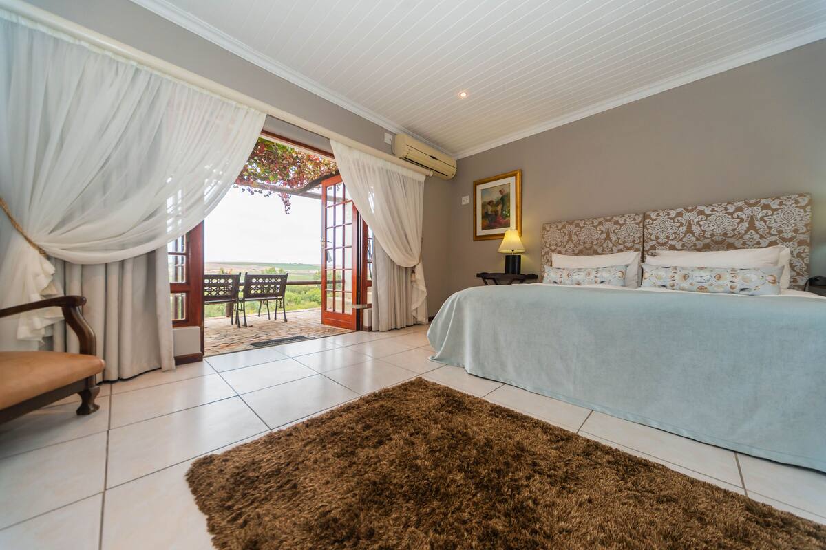 A bedroom with a bed, a chair, a rug, and a view through an open door.