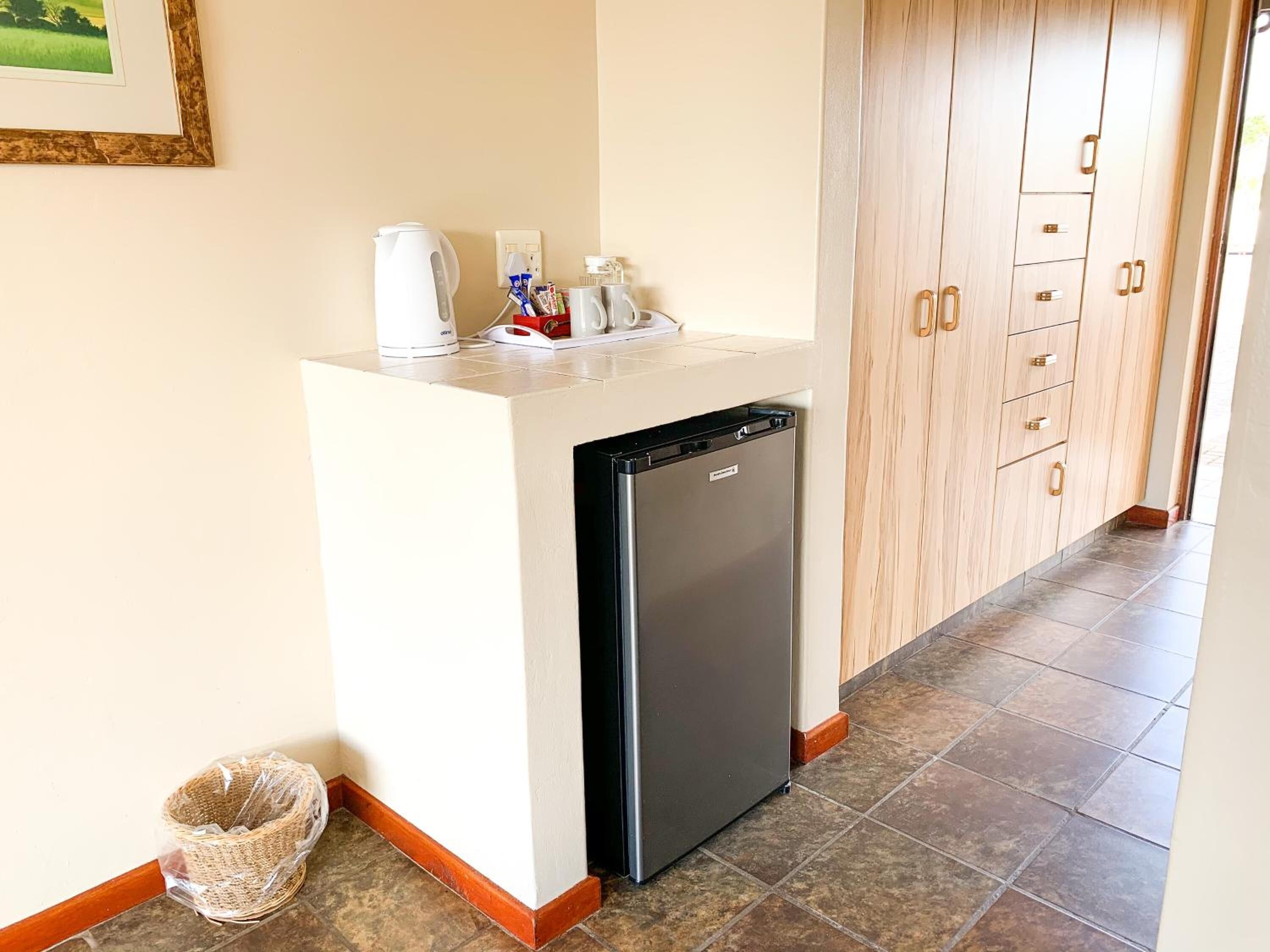 A compact kitchenette with a refrigerator, a kettle, and a coffee maker.