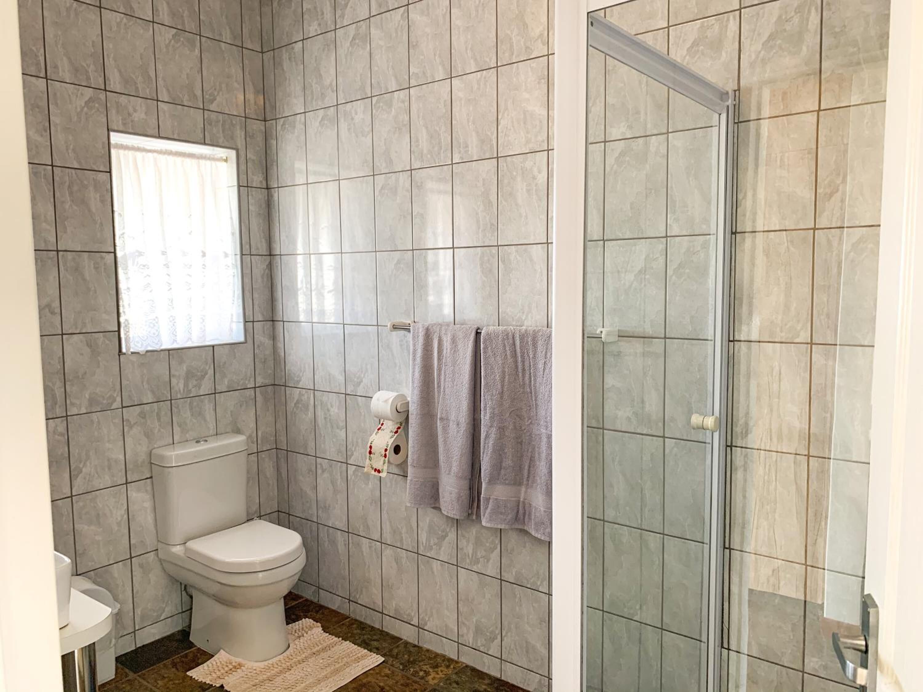 A bathroom with a toilet, a sink, a shower with a glass door, and a towel rack.