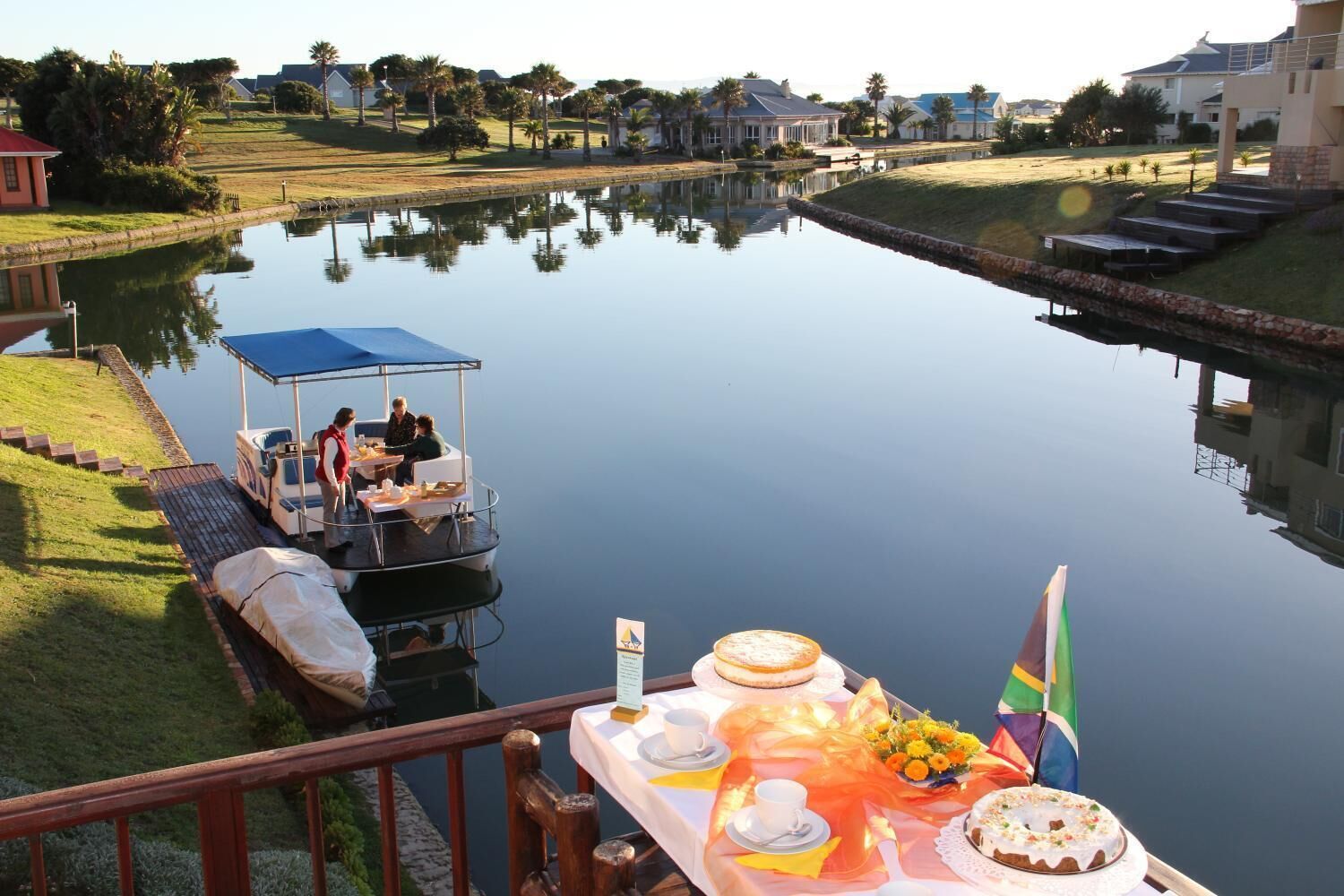 Un comedor con una mesa lista para una comida, un barco amarrado cerca e una bandera sobre la mesa.