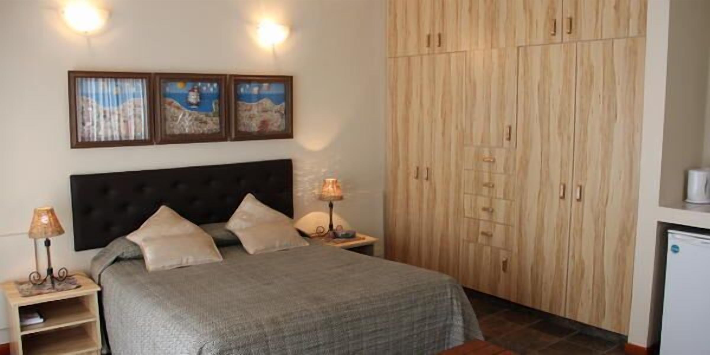 Un dormitorio con cama, mesitas de noche, armario y decoración en la pared.