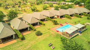 Un complexe hôtelier comprenant plusieurs chalets de style bungalow, une piscine centrale et une pelouse bien entretenue.