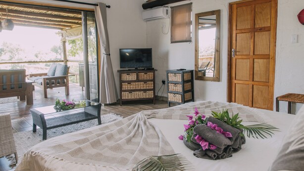 Une chambre à coucher avec un lit, une télévision, des paniers en osier et une porte en bois.
